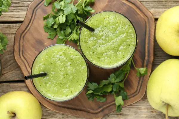 Sağlıklı maydanozlu buzlu içecek, tahta masada yapraklar ve elmalar, düz uzanmış