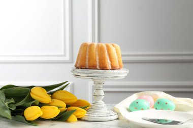Lezzetli kek, Paskalya yumurtası ve beyaz mermer masada laleler.