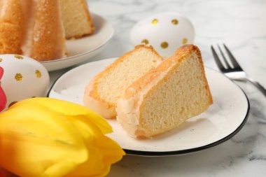 Lezzetli kek parçaları, Paskalya yumurtaları ve lale açık mermer masada, yakın plan.