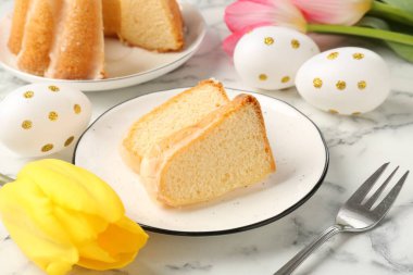 Lezzetli kek parçaları, Paskalya yumurtaları ve laleler açık mermer masada, yakın plan.