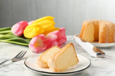 Lezzetli kek parçaları, Paskalya yumurtaları ve laleler açık mermer masada.