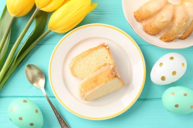 Lezzetli kek parçaları, paskalya yumurtaları ve laleler açık mavi ahşap masa, düz yatıyordu.