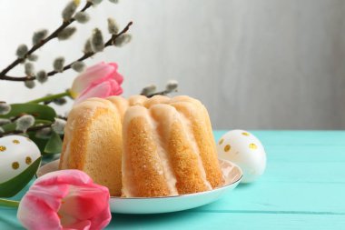 Lezzetli kek, Paskalya yumurtası, söğüt dalları ve açık mavi ahşap masada laleler.