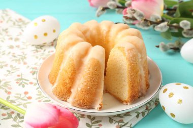 Lezzetli kek, Paskalya yumurtası, söğüt dalları ve açık mavi ahşap masada laleler, yakın plan.