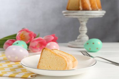 Lezzetli kek parçaları, beyaz ahşap masada paskalya yumurtaları ve laleler.