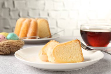 Lezzetli kek parçaları, paskalya yumurtası ve çay gri masada, yakın plan.