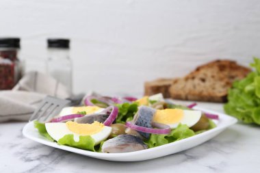 Ringa balıklı lezzetli salata, yumurta ve sebzeler beyaz mermer masada, yakın plan.