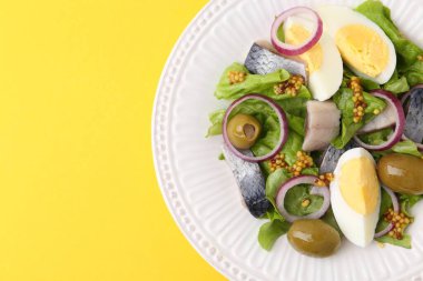 Ringa balıklı lezzetli salata, yumurta, hardal ve sebzeler sarı arka planda, üst manzara. Metin için boşluk