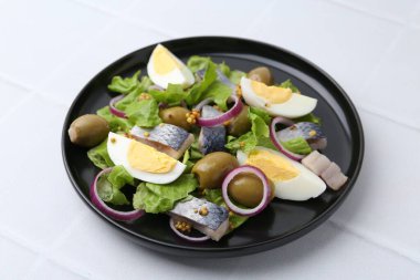 Ringa balıklı lezzetli salata, yumurta, hardal ve sebzeler beyaz fayanslı masada, yakın plan.