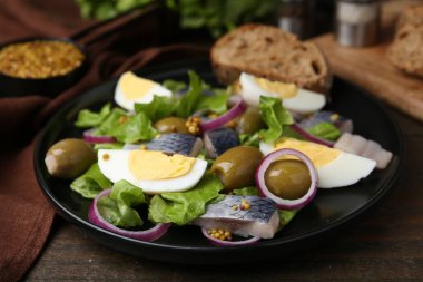 Ringa balıklı lezzetli salata, yumurta, hardal ve sebzeler ahşap masada, yakın plan.
