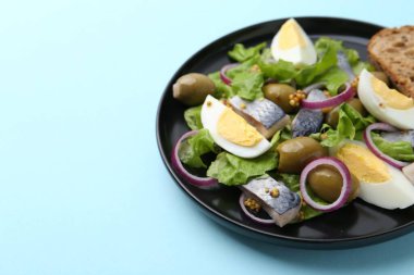 Açık mavi arka planda ringa balıklı, yumurtalı, hardallı ve sebzeli leziz salata, yakın plan. Metin için boşluk