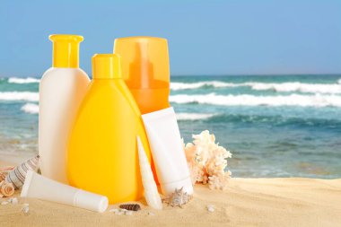 Okyanusa yakın kumsalda güneş kremi ürünleri ve deniz kabukları.