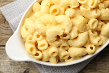 Peynir soslu lezzetli makarna ahşap masadaki kabın üstünde.