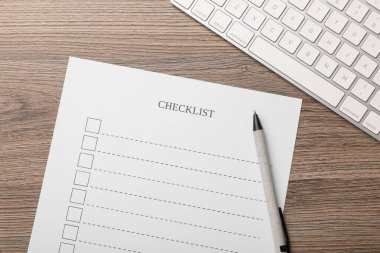 Tahta masa üzerinde kontrol listesi, kalem ve klavye, düz uzanma