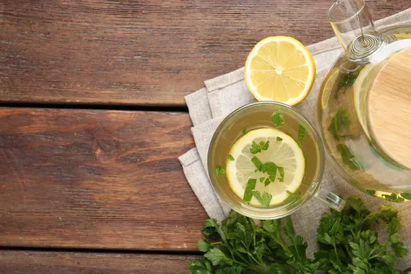 Tahta masa üzerinde limon dilimleri olan sağlıklı maydanoz çayı, düz yatak ve yazı için yer. Detoks içeceği