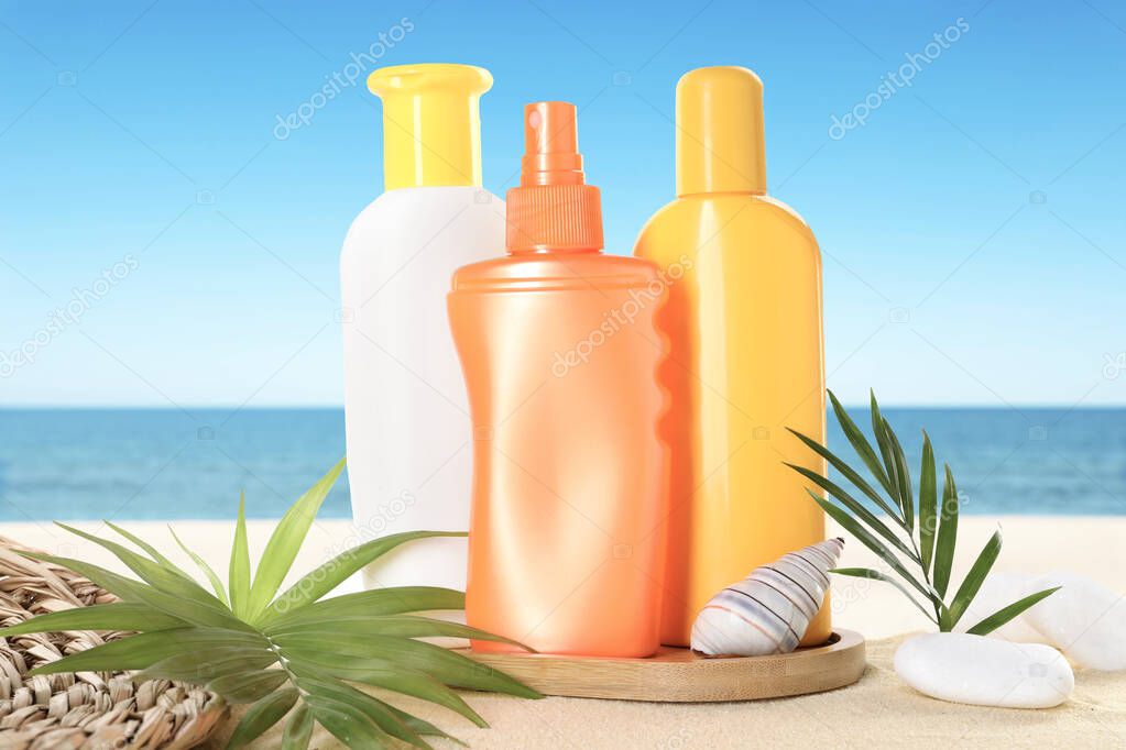 Sunscreen products on sandy beach near ocean