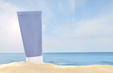 Deniz kenarındaki kumlu sahilde güneş kremi tüpü.