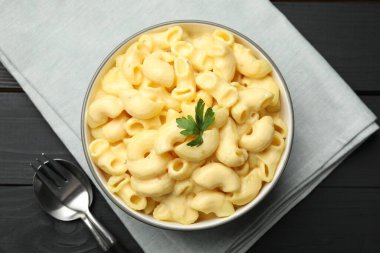 Siyah ahşap masada servis edilen maydanozlu lezzetli makarna ve peynir.