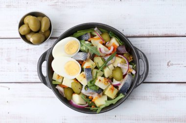 Ringa balıklı, yumurtalı, sebzeli ve beyaz ahşap masada zeytinli lezzetli salata.