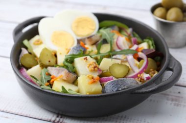 Ringa balıklı lezzetli salata, yumurta ve sebzeler beyaz ahşap masada, yakın plan.