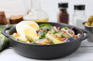 Ringa balıklı lezzetli salata, yumurta ve sebzeler beyaz ahşap masada, yakın plan.