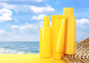 Deniz kenarındaki sarı masada güneş kremi ürünleri