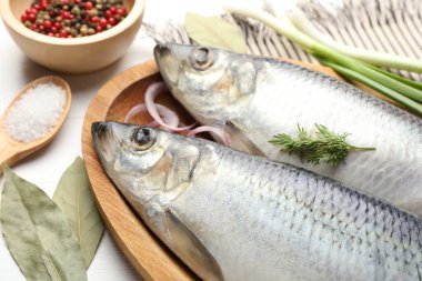 Tuzlu ringa balıkları ve baharatlar beyaz masada, yakın plan.