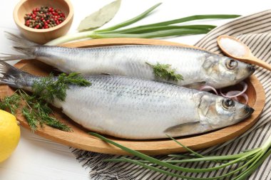 Tuzlu ringa balıkları ve baharatlar beyaz ahşap masada, yakın plan.