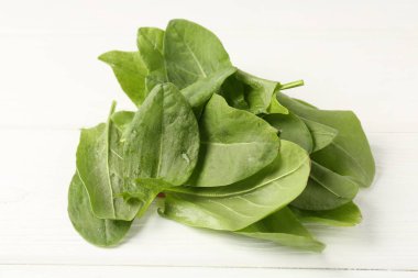 Taze yeşil kuş yaprakları beyaz ahşap masada, yakın plan.