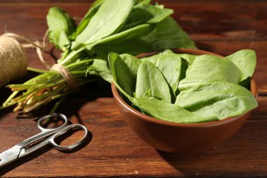Taze yeşil kuş yaprakları, makas ve sicim ahşap masada, yakın plan.