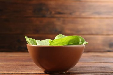 Taze yeşil kuş yaprakları kasede, ahşap masada, yakın plan.