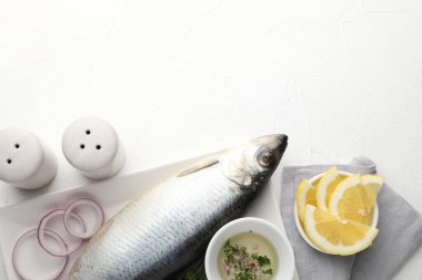 Tuzlu ringa balığı ve baharatlar beyaz masada, düz yerde. Metin için boşluk