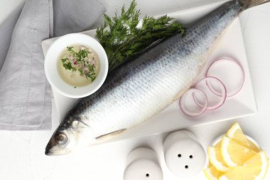 Tuzlu ringa balığı ve baharatlar beyaz masada, düz yerde.