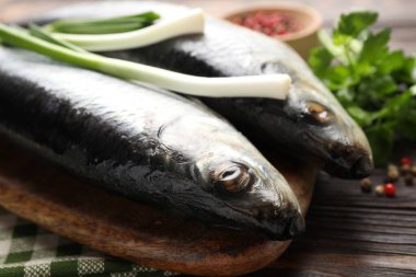 Ahşap masada tuzlanmış ringa balıkları ve baharatlar, yakın plan.