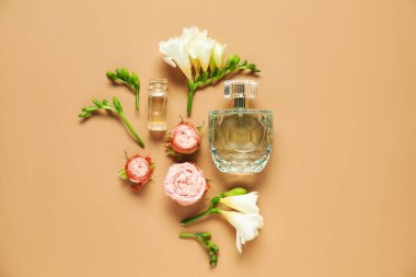 Düz kompozisyonda aromatik parfüm şişeleri ve bej arka planda güzel çiçekler vardı.