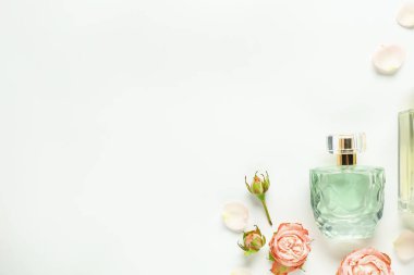 Kokulu parfüm şişeleri ve beyaz arka planda güzel çiçekler. Metin için boşluk