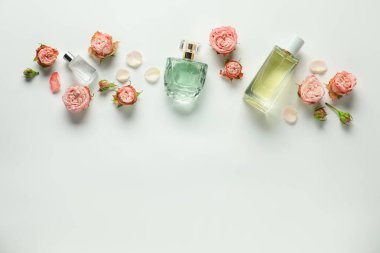 Kokulu parfüm şişeleri ve beyaz arka planda güzel çiçekler. Metin için boşluk