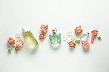 Düz kompozisyon, beyaz arka planda aromatik parfüm şişeleri ve güzel çiçekler vardı.
