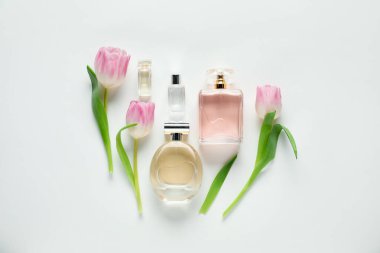 Aromatik parfüm şişeleri ve beyaz arka planda güzel çiçekler.