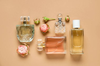 Düz kompozisyonda aromatik parfüm şişeleri ve bej arka planda güzel çiçekler vardı.