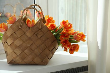 Pencere pervazında hasır çantanın içinde güzel laleler