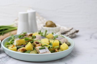 Ringa balıklı lezzetli salata ve beyaz mermer masada malzemeler, yakın plan.