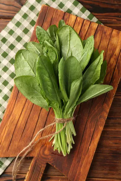 Tahta masanın üstünde taze yeşil kuş yaprakları var.