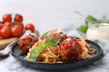 Köfteli lezzetli makarna, fesleğen ve peynir beyaz mermer masada, yakın plan.