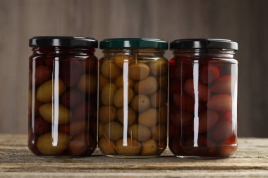 Tahta masada cam kavanozlarda zeytin turşusu.