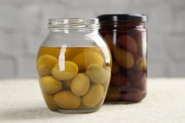 Kavanozlarda turşulu yeşil zeytin beyaz desenli masa, yakın çekim.