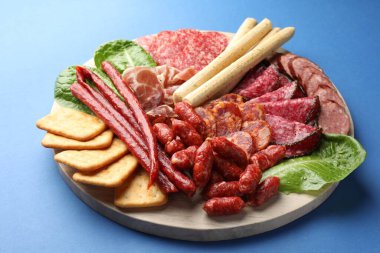 Mavi arka planda farklı tütsülenmiş sosisler ve diğer atıştırmalıklar, yakın plan