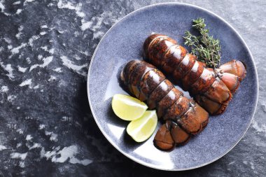Çiğ ıstakoz kuyruğu, kireç ve kekik karanlık masa, üst manzara. Metin için boşluk