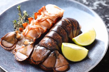 Çiğ ıstakoz kuyruğu, kireç ve kekik masada, yakın plan.