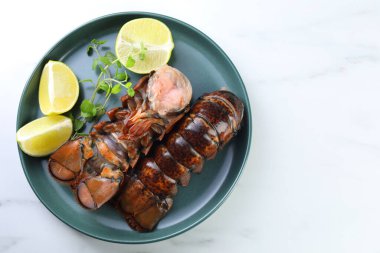 Çiğ ıstakoz kuyruğu, kireç ve mikro yeşiller beyaz mermer masa, üst manzara. Metin için boşluk